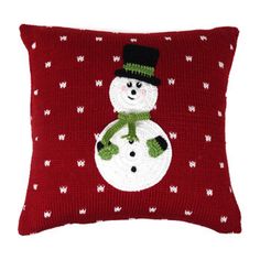 a red pillow with a snowman wearing a green hat and mittens on it