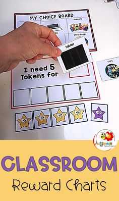 a close up of a person holding a piece of paper near a classroom reward chart