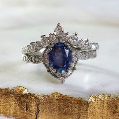 a blue and white diamond ring sitting on top of a piece of wood