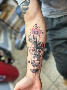 a person with a tattoo on their arm holding a cell phone in one hand and a clock in the other