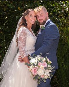 the bride and groom are posing for a photo in front of some greenery at their wedding