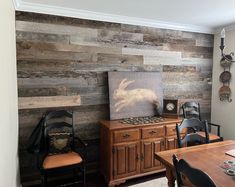 a dining room table with chairs and a painting on the wall behind it, in front of a wooden paneled wall