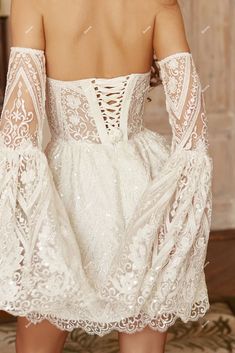 the back of a woman's white dress with sheer lace and openwork detailing