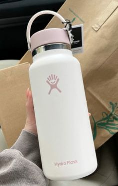 the hydro flask water bottle is white and has a pink logo on it as well