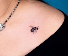 a woman's chest with a small tattoo of a bee on the left side