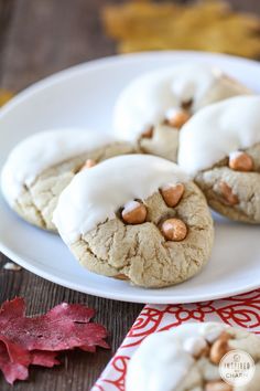 cookies with white icing and nuts are on a plate next to an autumn leaf