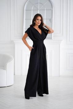 This stunning black jumpsuit is crafted from high-quality suiting fabric for a sleek and polished look. Featuring a deep V-neck and a double-layered bodice, it creates a chic, layered effect. The short sleeves resemble delicate wings, adding a touch of lightness and grace to the design. The waistline is accentuated to visually enhance your figure, while the wide-leg pants feature pleats for extra volume and comfort. A zipper at the back ensures a perfect fit. Ideal for formal events, parties, or any special occasion, this jumpsuit offers both style and comfort. Length: 145 cm Shoes To Wear With Jumpsuit Wedding, Plus Size Wedding Jumpsuit, Jumpsuit Outfit Formal, Mother Of The Bride Pants Outfit, Alternative Wedding Outfit, Mother Of The Bride Jumpsuit, Elegante Jumpsuits, Formal Plus Size, Bride Jumpsuit