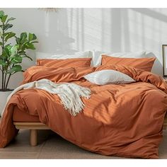 a bed with an orange comforter and pillows