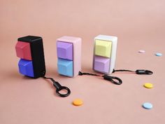 three different colored blocks and scissors on a pink surface