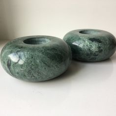 two green marble vases sitting on top of a white table next to each other