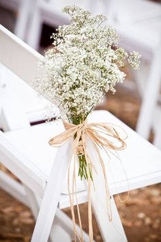 a bouquet of baby's breath sitting on top of a white chair with ribbon