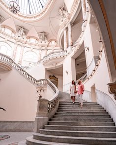 two people walking up some stairs in a building