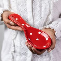 a woman holding a red spoon with white polka dots on it