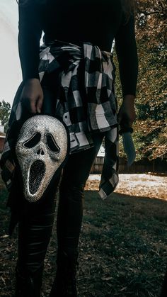 a woman in black and white is holding a silver bag with a skull mask on it