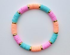 a colorful bracelet with gold beads and pink, blue, and yellow tassels