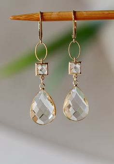 Beautiful, elegant Earrings with Clear Faceted Glass Square Connectors 7 x 7 mm Faceted Clear Glass Drops clear like drop of Water 17 x 11 mm. in Gold plated Bezel frame Gold plated Lever back Ear Clasp. The total length is 2.25 inches or 58 mm long.  Your order will be wrapped and shipped in jewelry gift box. * * * * * * * * * * * * * * * * * * * * * * * * * * * * * * * * * * * * * * * * * *  If you would like to order this item as a gift you can leave a personalized note for the receiver durin Cheap Clear Drop Earrings, Briolette Yellow Gold Earrings For Weddings, Yellow Gold Briolette Earrings For Wedding, Elegant Gold Faceted Crystal Earrings, Elegant Briolette Crystal Earrings, Formal Clear Teardrop Earrings, Elegant Briolette Faceted Crystal Earrings, Elegant Faceted Briolette Crystal Earrings, Elegant Drop Earrings With Faceted Details