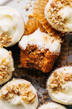 some cupcakes with white frosting and nuts on top are sitting in a pan