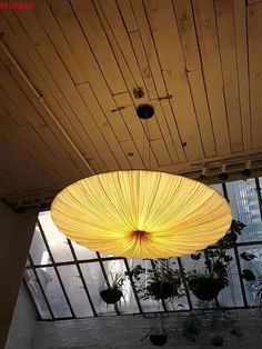 a large light fixture hanging from the ceiling in a room filled with potted plants