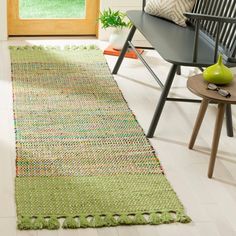 a green rug on the floor in front of a wooden door with a black bench