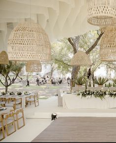 the tables are set up for an outdoor event with white linens and wicker hanging from the ceiling