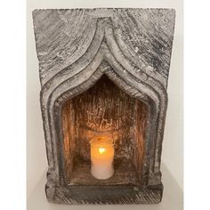 a candle is lit in an old, carved stone fireplace with a white wax finish