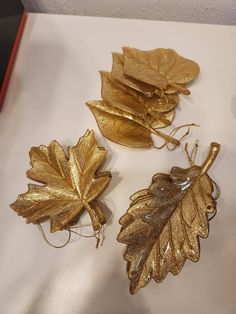 three gold leaf ornaments sitting on top of a table