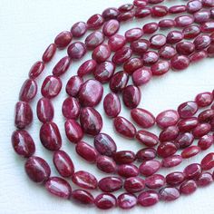 a long strand of red glass beads on a white surface