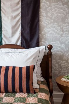 a bed with two pillows on top of it next to a night stand and side table