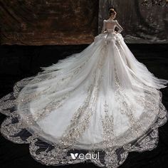 a woman in a white wedding dress standing on a black surface with an intricately designed veil