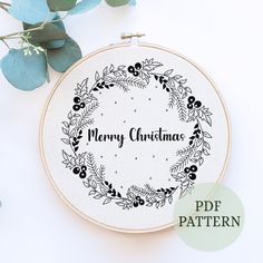 a cross stitch christmas wreath with the words merry christmas in black and white on it