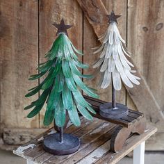 two wooden christmas trees sitting on top of a piece of wood next to each other