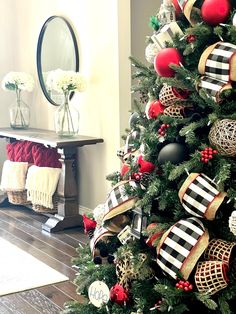 a decorated christmas tree with red and black ornaments on it's branches in front of a mirror