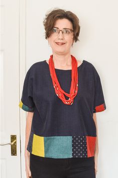 a woman standing in front of a white door wearing a red necklace and black pants