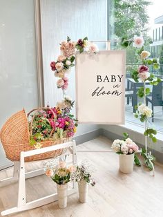 a sign that says baby in bloom next to some flowers and potted plants on a stand