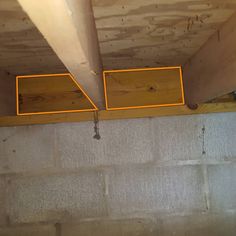 two yellow boxes are hanging from the ceiling in an unfinished room with concrete walls and wood beams