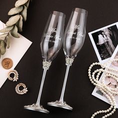 two champagne flutes sitting on top of a table next to pearls and other items,