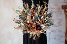 a vase filled with dried flowers and feathers