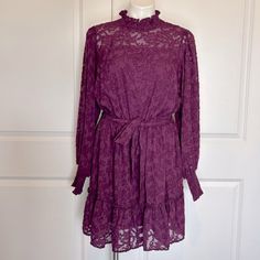 a purple lace dress on a mannequin stand in front of a white door