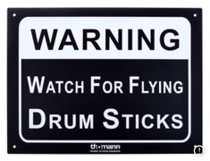 a black and white warning sign with the words watch for flying drum sticks on it