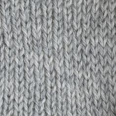 a close up view of the texture of a knitted fabric with grey and white colors