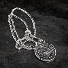 This stainless steel necklace is perfect for those who want to add a little bit of mythology to their wardrobe. The shield style pendant features the mythical serpent Jormungand, encircling a Valknut symbol. Whether you're dressing up for a day at the office or dressing down for a night out on the town, this necklace is sure to make a statement. Also features a Helm of Awe on the reverse with the inscription: "The brave shall live forever in the halls of Valhalla" Pendant is approx. 1.5" across Viking Style Stainless Steel Necklace For Gift, Viking Style Engraved Round Pendant Necklace, Viking Style Engraved Metal Necklaces, Viking Style Stainless Steel Pendant Necklace, Viking Style Silver Stainless Steel Necklaces, Silver Viking Stainless Steel Necklaces, Viking Style Stainless Steel Silver Necklaces, Symbolic Silver Tarnish Resistant Medallion Necklace, Symbolic Silver Medallion Necklace