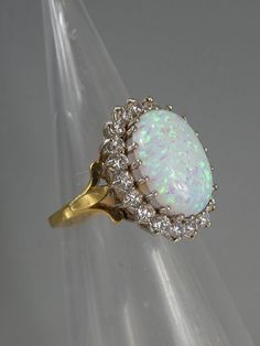 Elevate your style with this stunning Cultured Opal Ring, crafted in Sterling Silver with 925 metal purity and Gold Finished. The beautifully crafted ring features a mesmerizing Central Cultured opal stone surrounded by sparkling clear cubic zirconia's adding a touch of elegance to your outfit. The ring size is M 1/2, making it a perfect addition to your fine jewellery collection. This exquisite piece can be worn to any occasion and will leave a lasting impression. The combination of silver and Exquisite Opal And Diamond Ring, Exquisite Diamond Opal Ring, Exquisite Opal Diamond Ring, Formal Multi-stone Opal Ring With Diamonds, Formal Multi-stone Diamond Opal Ring, Heirloom White Opal Ring, Diamond White Opal Ring Fine Jewelry, Diamond White Round Opal Jewelry, White Opal Ring With Round Stone