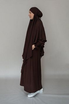 Introducing the Myyla Prayer Gown Umrah Abaya Dress, a stunning and elegant piece of modest wear that is perfect for any prayer or Hajj occasion. Made by the renowned brand Annah Hariri, this abaya dress is crafted with high-quality non-wrinkling fabric that ensures that you always look your best.The Myyla Prayer Gown features a beautiful dark coffee color and is designed as a completely covered one-piece abaya with an A-cut style that flatters your figure. The dress comes with pockets, which ar Modest Brown Maxi Dress, Brown Khimar For Eid, Brown Long Sleeve Khimar For Eid, Brown Long Thobe For Eid, Modest Long Brown Maxi Dress, Modest Brown Abaya For Eid, Umrah Abaya, Annah Hariri, Dark Coffee