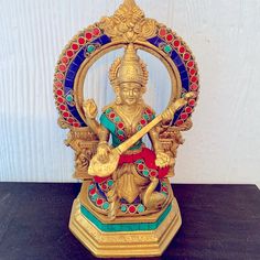 a golden statue sitting on top of a black table next to a white wall with red, blue and green accents