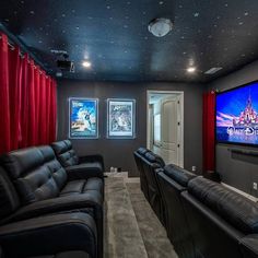 a home theater with black leather couches and red curtains