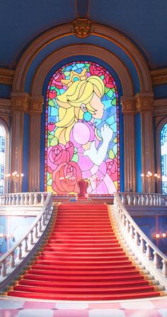 a large stained glass window above a red staircase leading up to the second floor with flowers on it