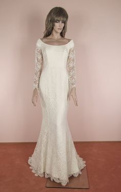 a mannequin wearing a white dress with long sleeves and lace on the shoulders