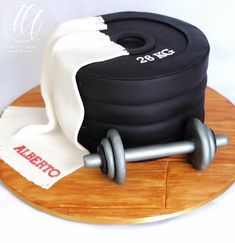 a cake that is on top of a wooden board with a towel and two dumbbells