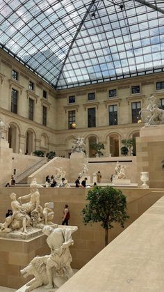 the inside of a building with many statues and people walking around in front of it