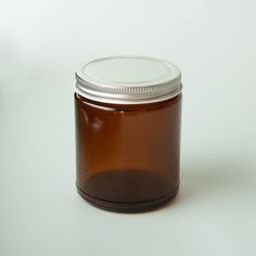 a glass jar filled with brown liquid sitting on top of a white table next to a cup